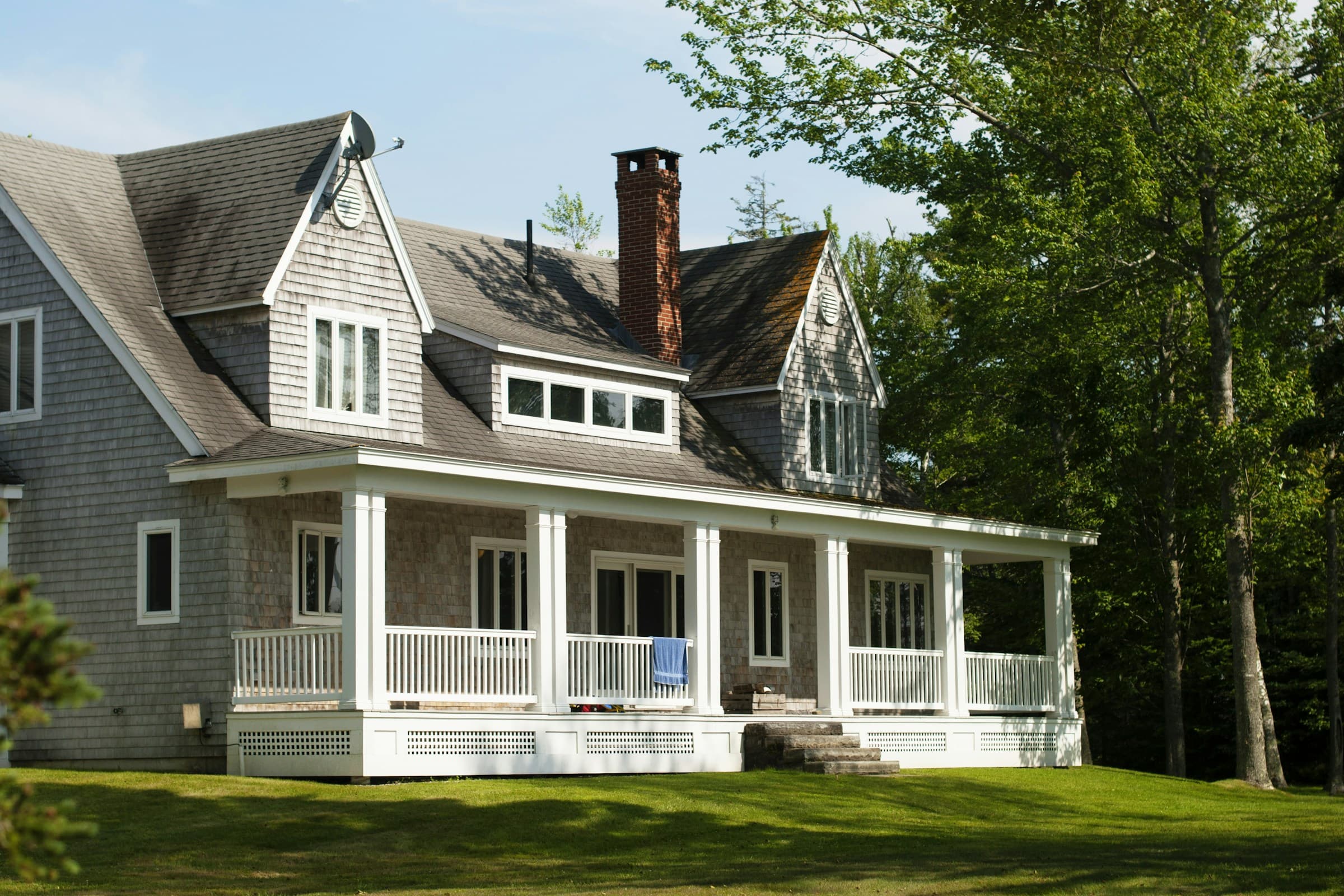 Shingle-style New England home with a wraparound porch